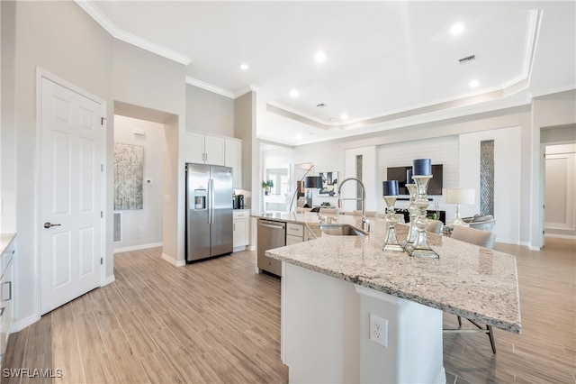 kitchen with a kitchen breakfast bar, stainless steel appliances, sink, white cabinets, and a large island