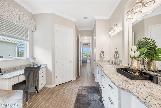 bathroom featuring vanity, wood-type flooring, ornamental molding, and a wealth of natural light