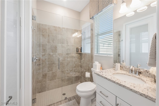 bathroom featuring tile patterned floors, vanity, a shower with shower door, and toilet