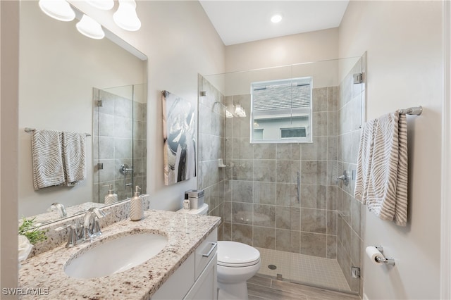 bathroom with hardwood / wood-style flooring, vanity, a shower with shower door, and toilet