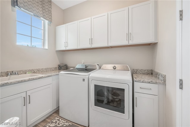 washroom featuring washer and clothes dryer, cabinets, wood-type flooring, and sink