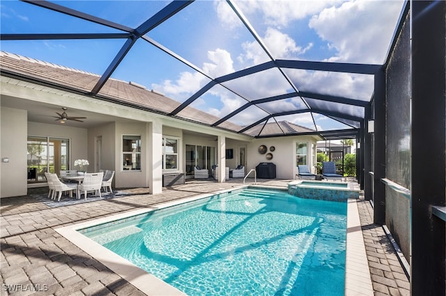 view of pool with glass enclosure, ceiling fan, a patio, and an in ground hot tub