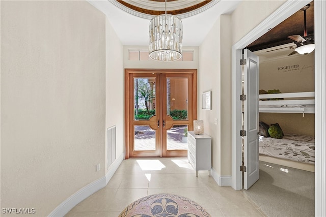 tiled entrance foyer with ceiling fan with notable chandelier and french doors