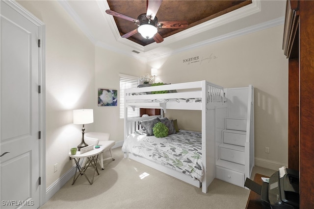 bedroom featuring ceiling fan, a raised ceiling, carpet floors, and crown molding