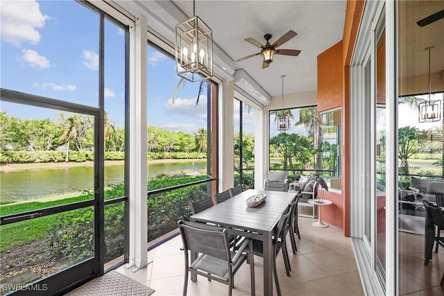 sunroom with ceiling fan with notable chandelier and a water view