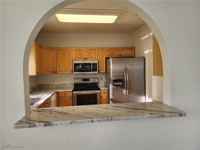 kitchen with light stone counters, light brown cabinetry, and appliances with stainless steel finishes