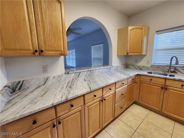 kitchen featuring light tile patterned floors, light stone counters, ceiling fan, and sink