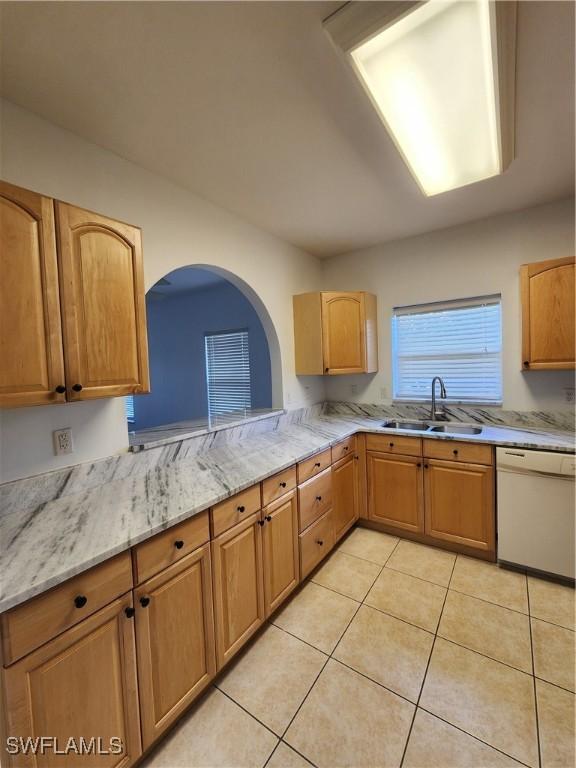 kitchen with dishwasher, light tile patterned floors, light stone counters, and sink