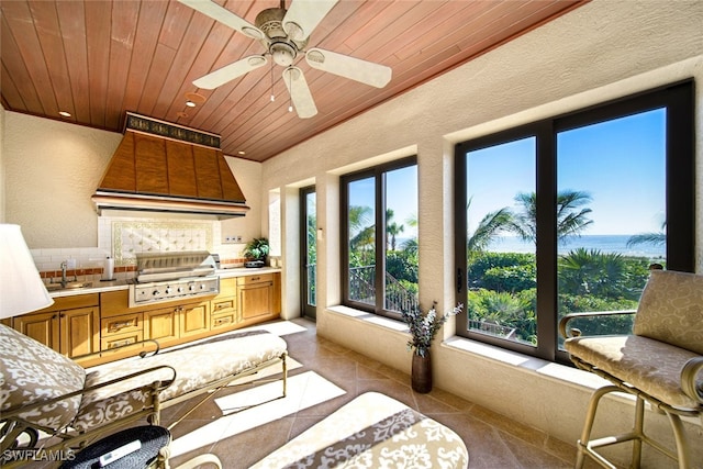 interior space with ceiling fan, a water view, wood ceiling, and sink