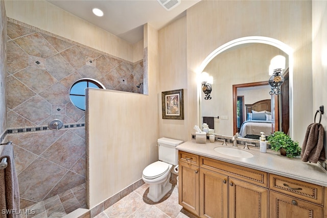 bathroom featuring a tile shower, vanity, and toilet