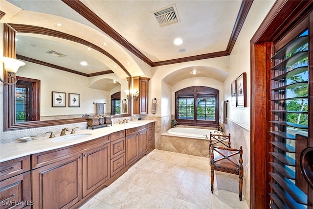 bathroom with a relaxing tiled tub, ornamental molding, and vanity