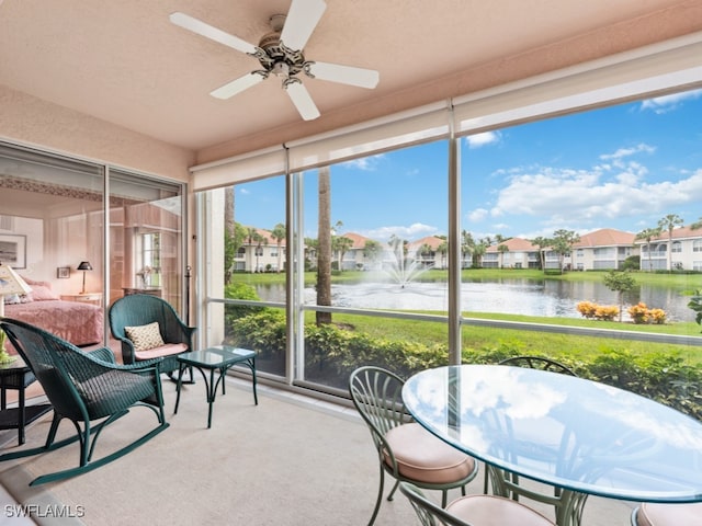 sunroom featuring ceiling fan, a water view, and a healthy amount of sunlight