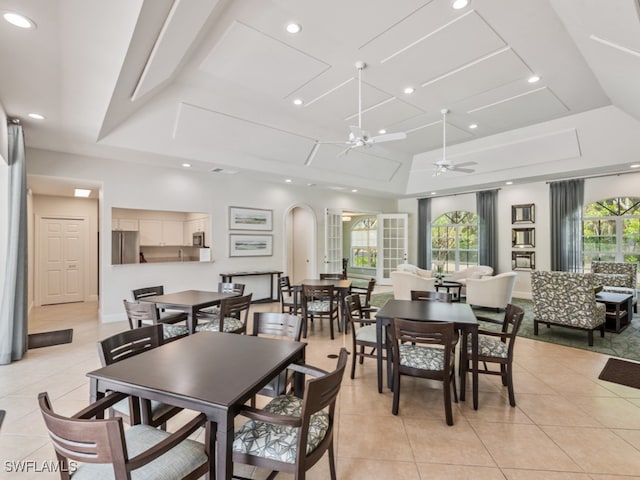 tiled dining space featuring ceiling fan and a raised ceiling