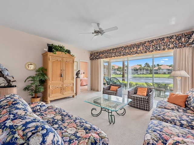 carpeted living room featuring ceiling fan and a water view