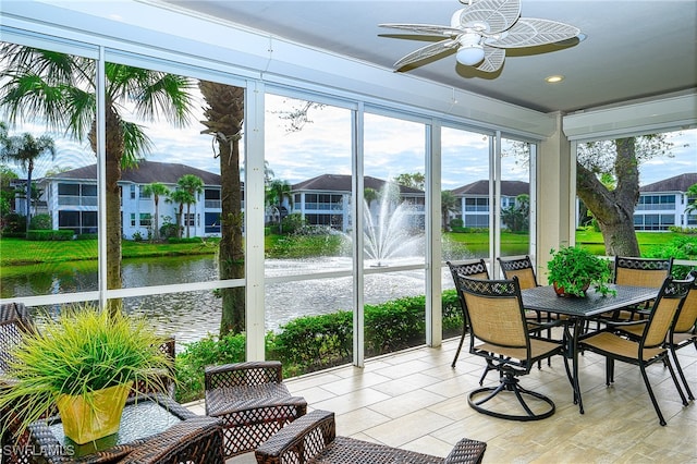 sunroom with ceiling fan and a water view