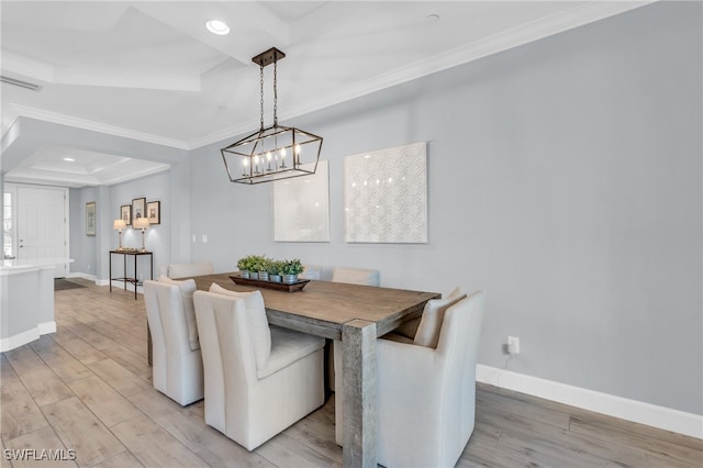 dining space with a raised ceiling, crown molding, a chandelier, and light wood-type flooring