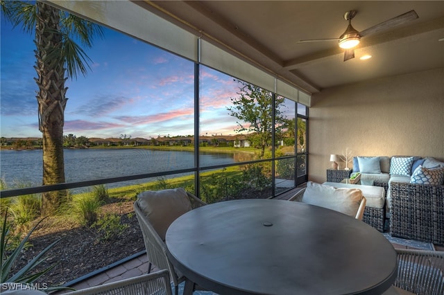 sunroom featuring ceiling fan and a water view