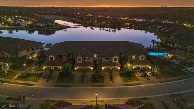 aerial view at dusk featuring a water view