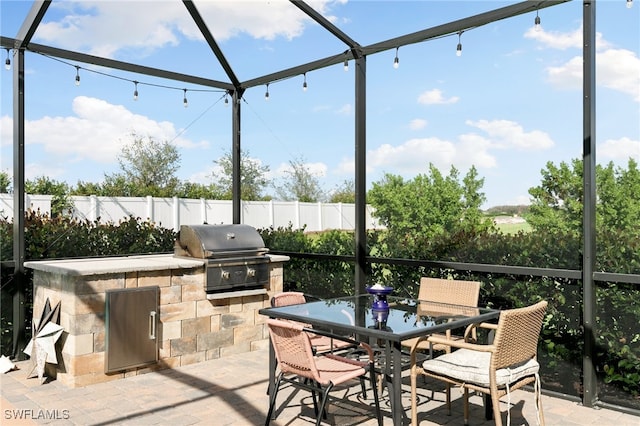 view of patio featuring glass enclosure, area for grilling, and a grill