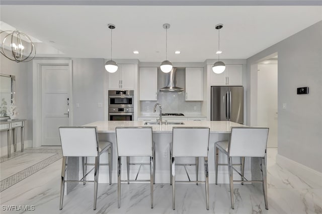 kitchen featuring sink, an island with sink, stainless steel appliances, and wall chimney range hood