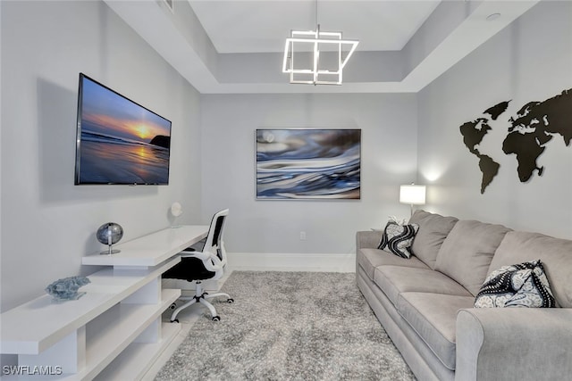 home office with a chandelier and a raised ceiling