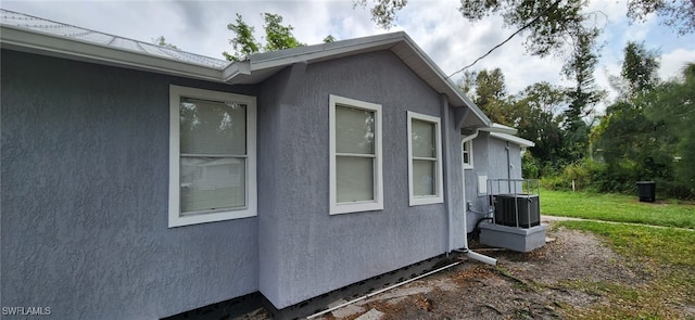 view of side of property featuring central AC unit and a yard