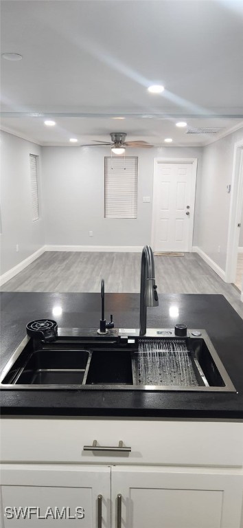 kitchen featuring ceiling fan, white cabinets, light hardwood / wood-style flooring, and sink