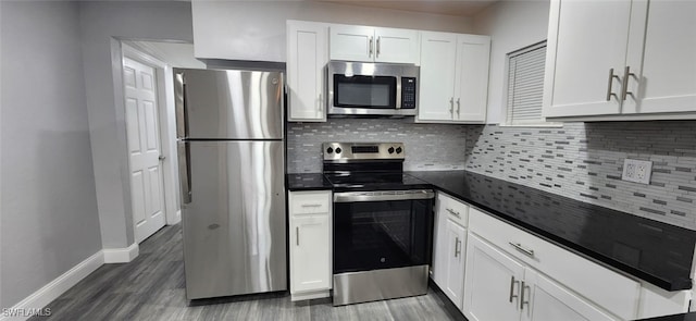 kitchen with dark wood-type flooring, appliances with stainless steel finishes, backsplash, and white cabinets