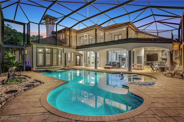 pool at dusk featuring an in ground hot tub, a patio, glass enclosure, and ceiling fan