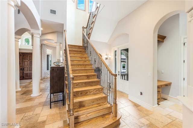 stairs featuring a towering ceiling and decorative columns