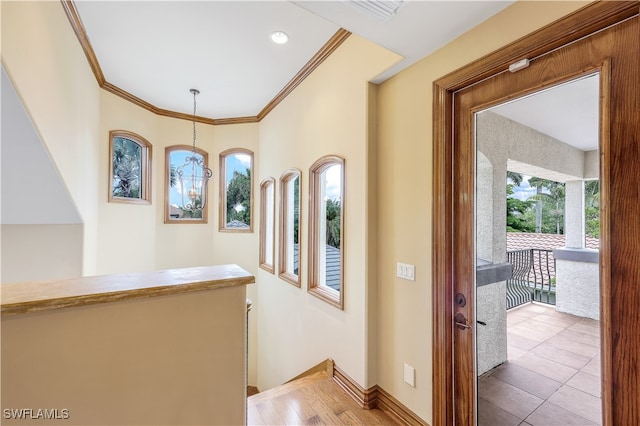 corridor with a chandelier, wood-type flooring, and ornamental molding