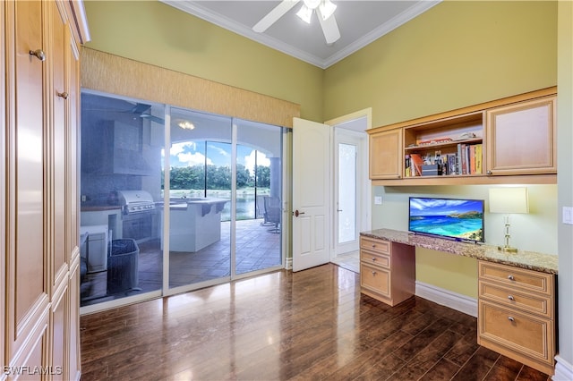 unfurnished office featuring crown molding, ceiling fan, built in desk, and dark hardwood / wood-style floors