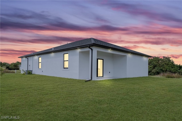 property exterior at dusk with a lawn