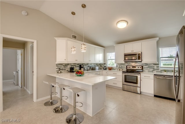 kitchen with kitchen peninsula, appliances with stainless steel finishes, white cabinets, and pendant lighting