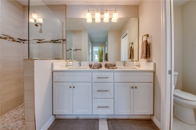 bathroom with vanity, toilet, and tiled shower