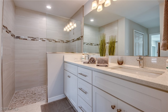 bathroom with tile patterned floors, vanity, and a tile shower