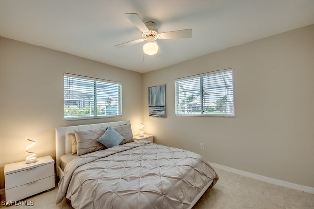 bedroom with multiple windows, ceiling fan, and light colored carpet