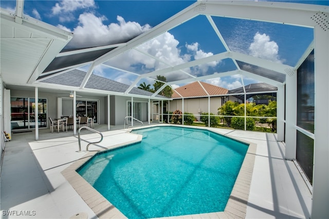 view of pool featuring glass enclosure, ceiling fan, and a patio