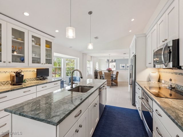 kitchen featuring sink, backsplash, lofted ceiling, a center island with sink, and appliances with stainless steel finishes