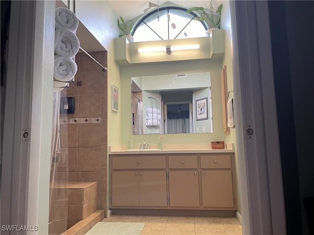 bathroom with tile patterned flooring, vanity, and tiled shower