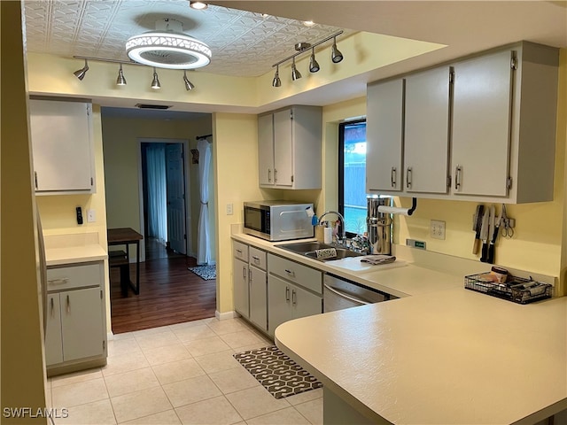 kitchen with gray cabinetry, dishwasher, sink, kitchen peninsula, and light tile patterned floors