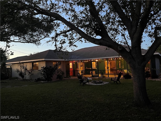 back house at dusk featuring a yard and an outdoor fire pit