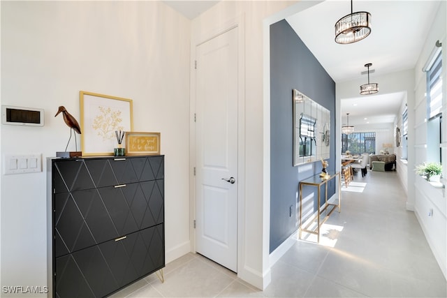 hallway featuring light tile patterned floors and a notable chandelier