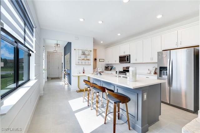 kitchen featuring stainless steel appliances, sink, a center island with sink, white cabinetry, and a breakfast bar area