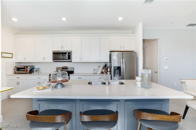 kitchen featuring a breakfast bar, sink, an island with sink, and stainless steel appliances