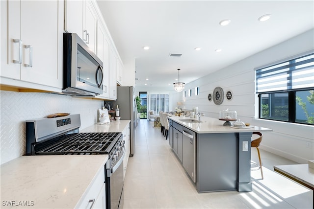 kitchen featuring white cabinets, a breakfast bar, stainless steel appliances, and hanging light fixtures