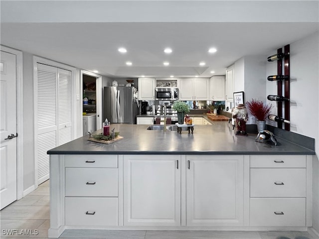 kitchen with appliances with stainless steel finishes, independent washer and dryer, white cabinetry, and sink