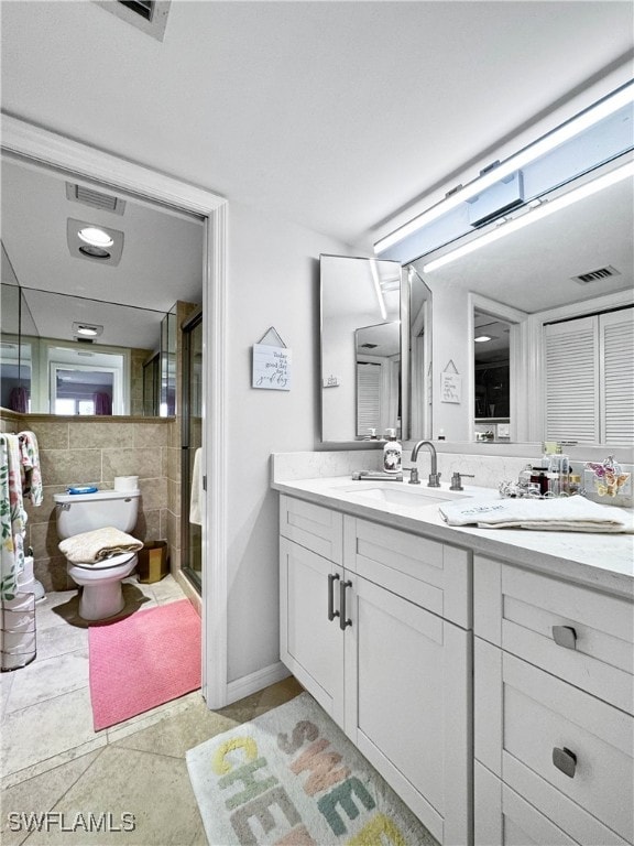 bathroom featuring tile patterned flooring, vanity, an enclosed shower, and toilet