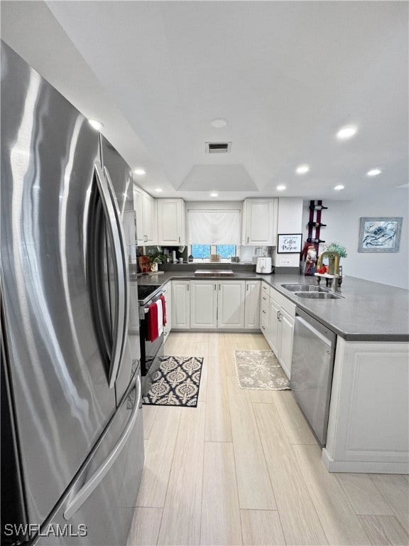 kitchen featuring sink, stainless steel appliances, kitchen peninsula, light hardwood / wood-style floors, and white cabinets