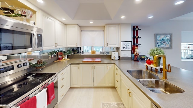 kitchen with kitchen peninsula, appliances with stainless steel finishes, a wealth of natural light, and sink